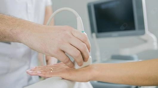 Um profissional de saúde realizando um exame de ultrassom em reumatologia na mão de uma paciente