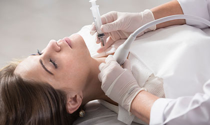 Profissional de saúde realizando ultrassonografia e biópsia da tireóide no pescoço da paciente