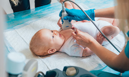 Estudante de pediatria realizando ultrassonografia em um recém-nascido