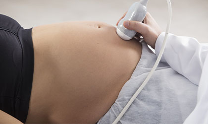Profissional de saúde realizando ultrassonografia na barriga da paciente gestante
