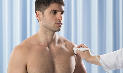 Paciente sem camisa sendo examinado pelo profissional de saúde usando ultrassonografia