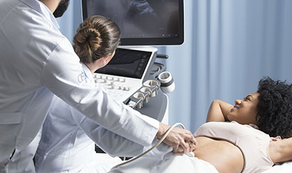 Profissionais de saúde realizando ultrassonografia no abdômen de uma paciente.