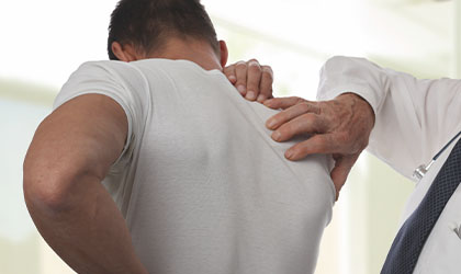 Médico examinando com as mãos as costas de um paciente