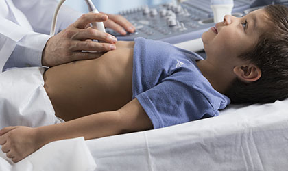 Profissional de saúde realizando ultrassonografia no abdômen em uma criança