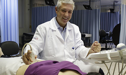 Profissional de saúde sorrindo realizando uma ultrassonografia fetal