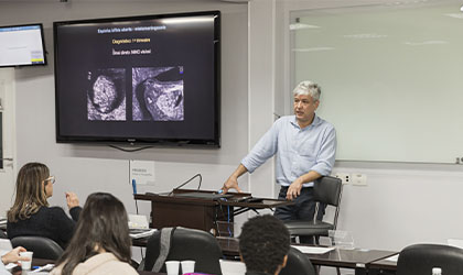 Professor em sala de aula com monitor mostrando radiografia no curso de Atualização e Preparatório de medicina fetal