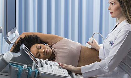 Profissional de saúde realizando ultrassonografia na lateral do corpo de uma paciente.
