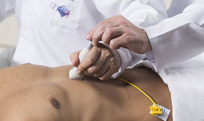 Profissional de saúde realizando ecocardiografia no tórax do paciente que está sem camisa